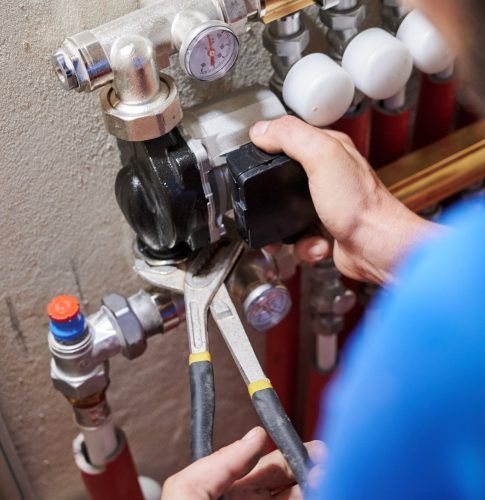 Une personne resserrant un écrou d'un chauffage.