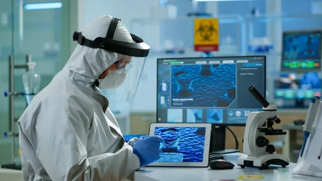 Un científico con un traje protector está mirando una tableta en un laboratorio.