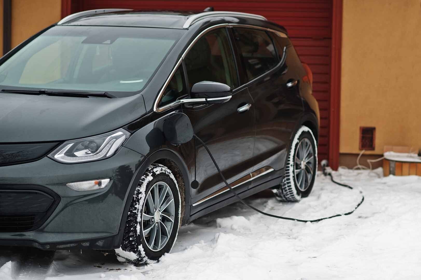 Voiture noire électrique devant une maison