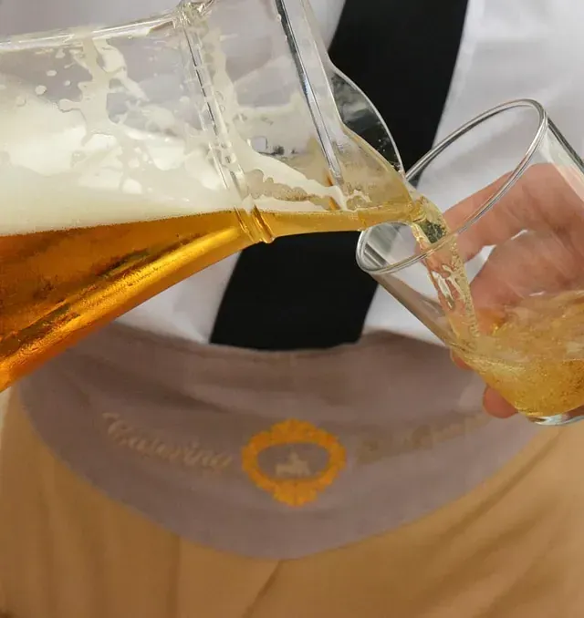 Una persona sirviendo un vaso de cerveza de una jarra