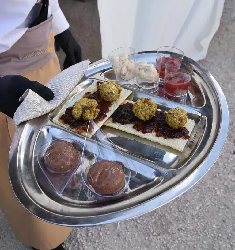 Una persona sostiene una bandeja de comida y bebidas.
