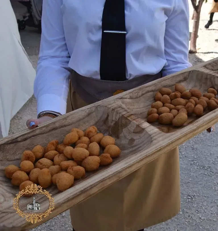 Una mujer con corbata sostiene una bandeja de madera con comida.