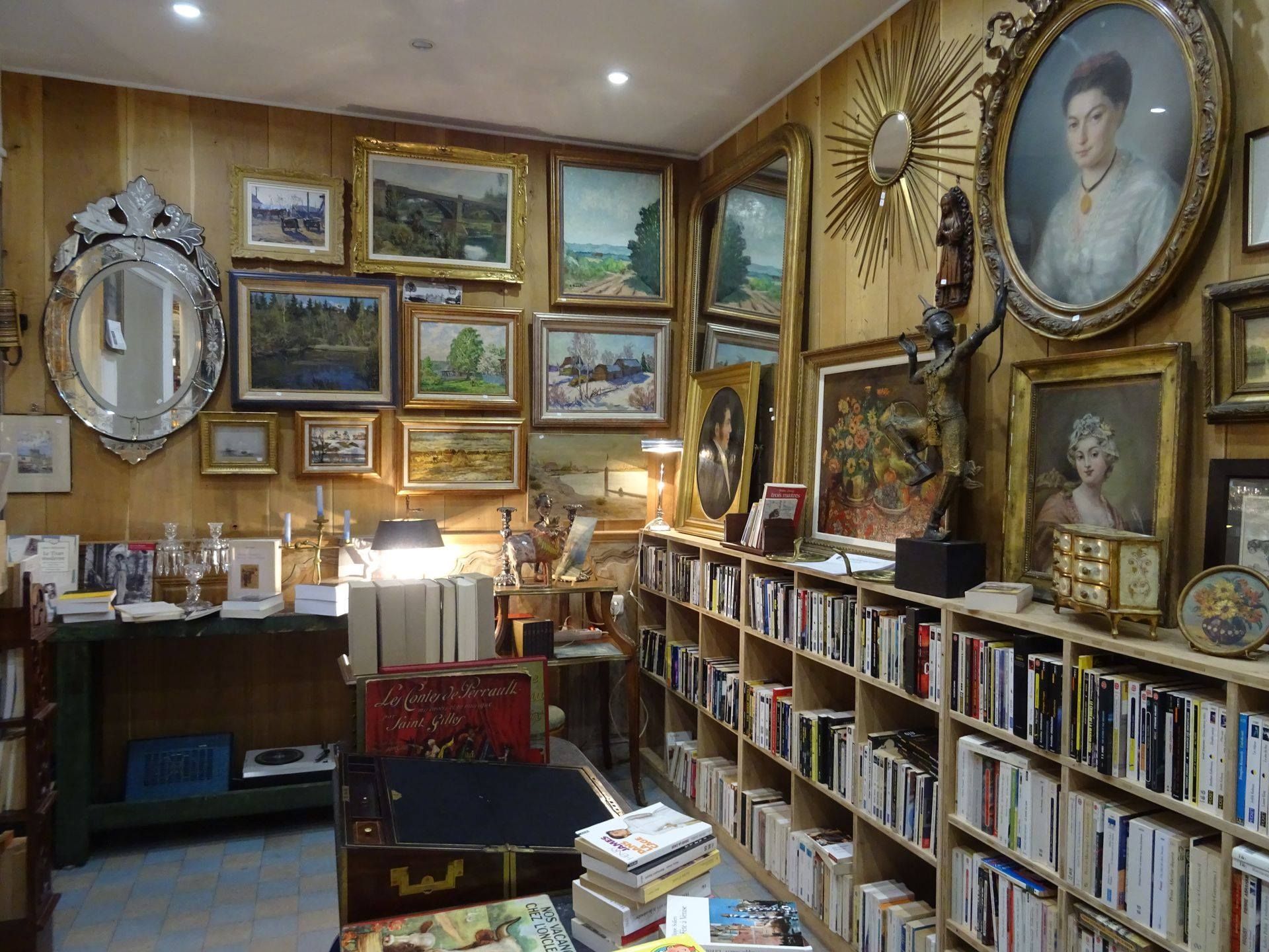 Pièce avec une petite bibliothèque et des tableaux aux murs.