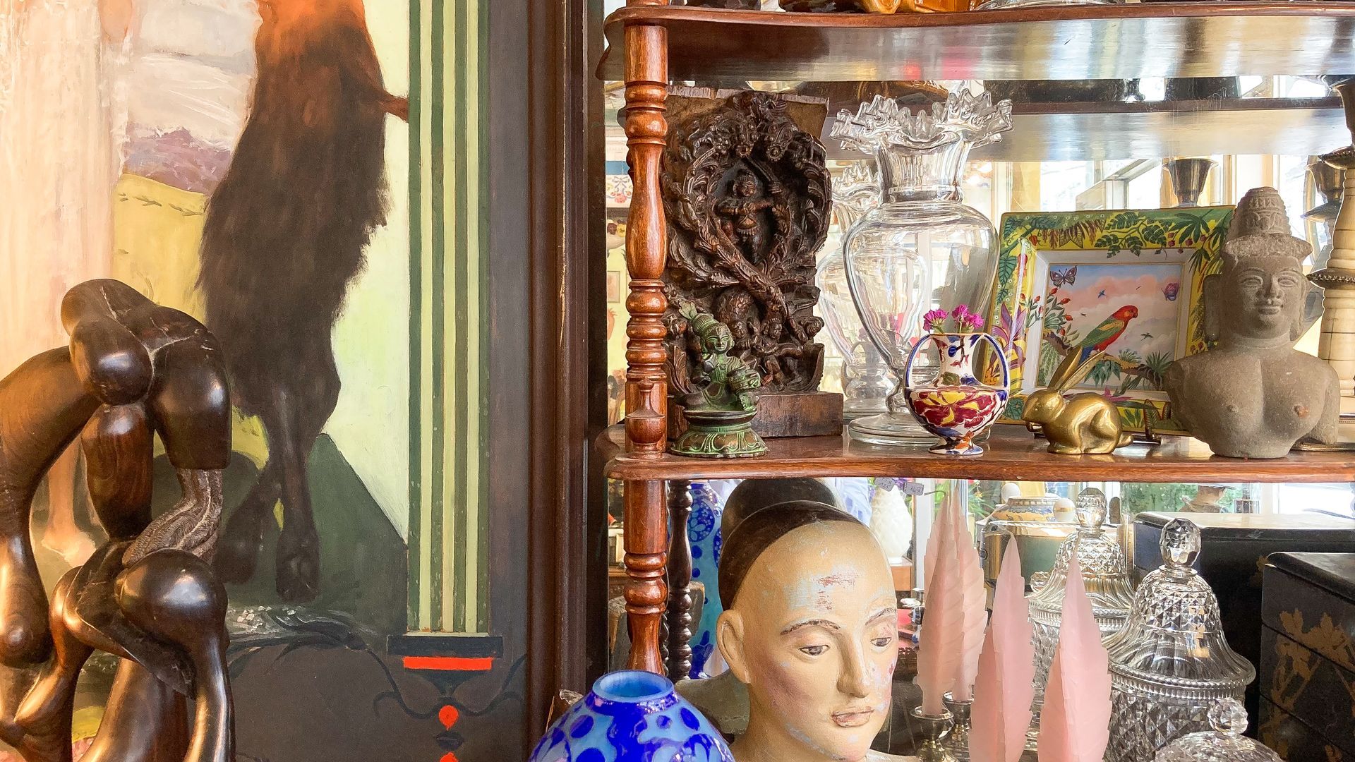 Étagère en bois avec des vases, sculptures, tableau et autres bibelots.