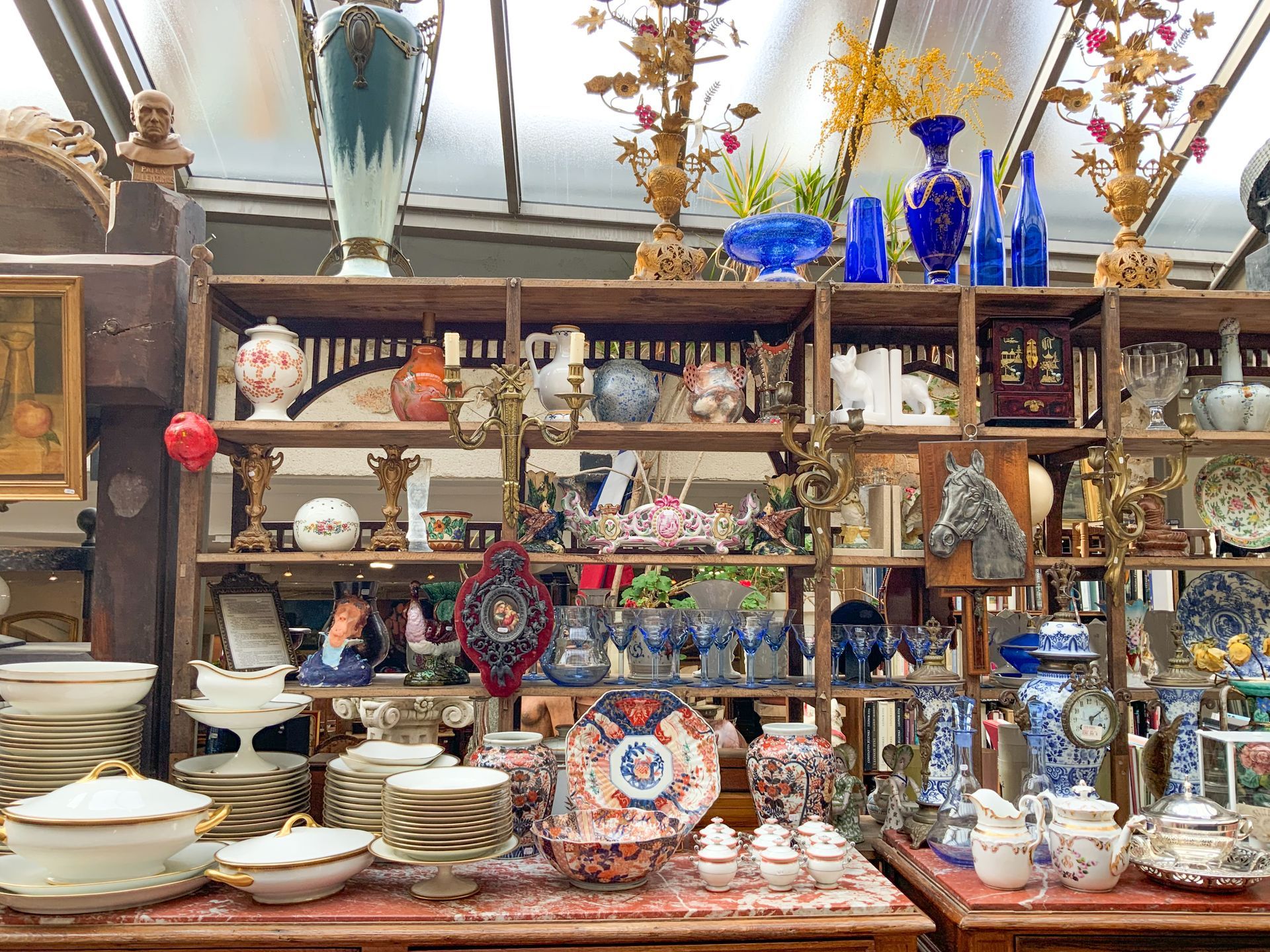 Grande étagère en bois avec des vases, des assiettes, des théières.