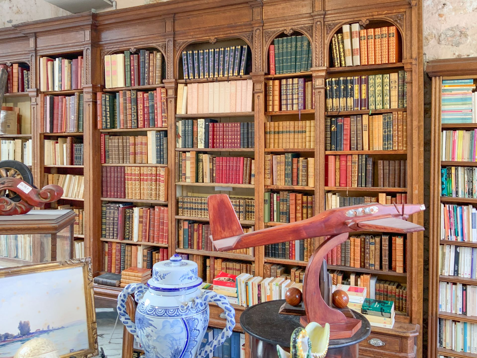 Grande bibliothèque murale en bois avec un avion miniature rouge devant.