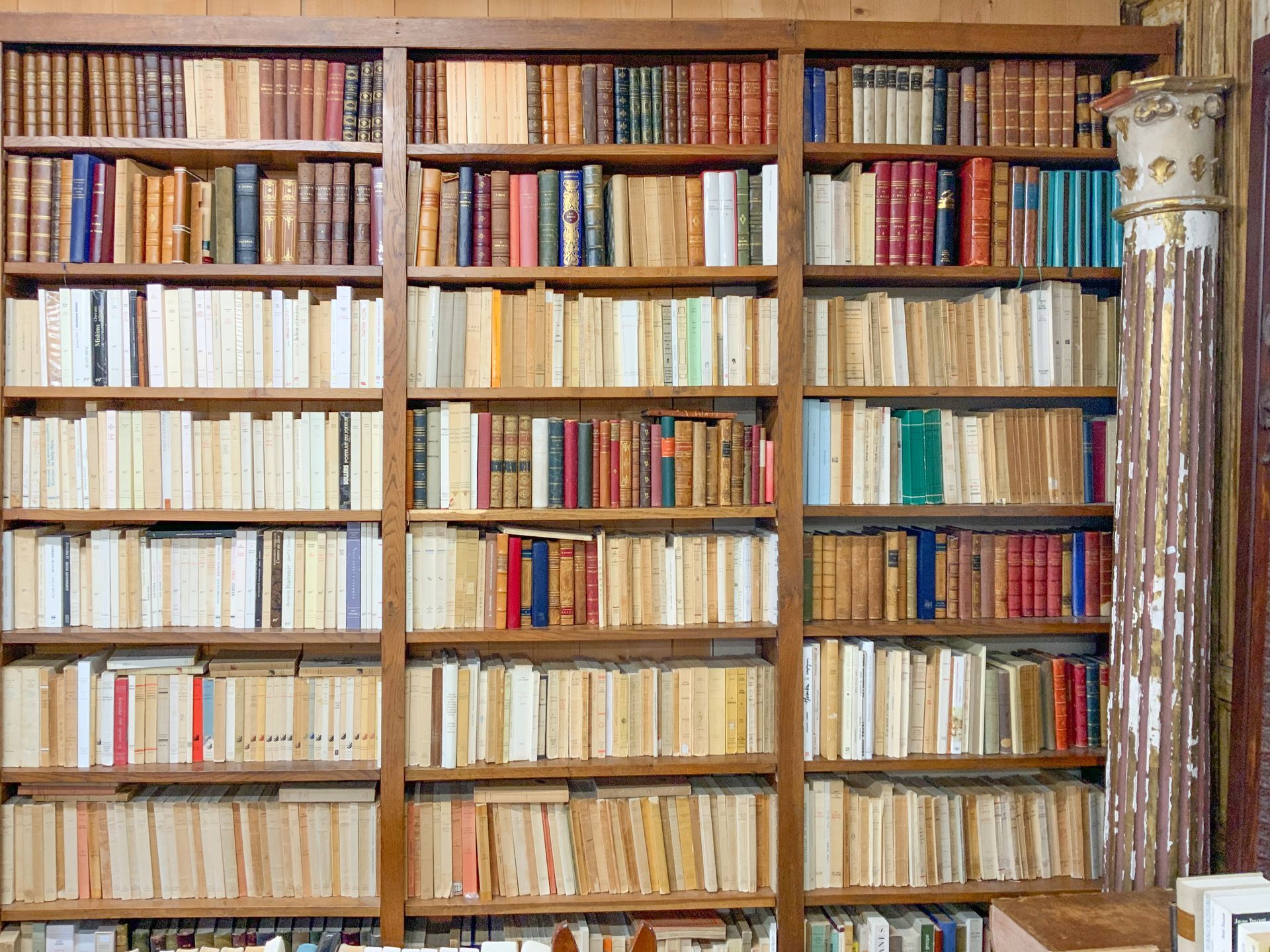 Grande bibliothèque murale avec un ancien pilier en pierre à côté.