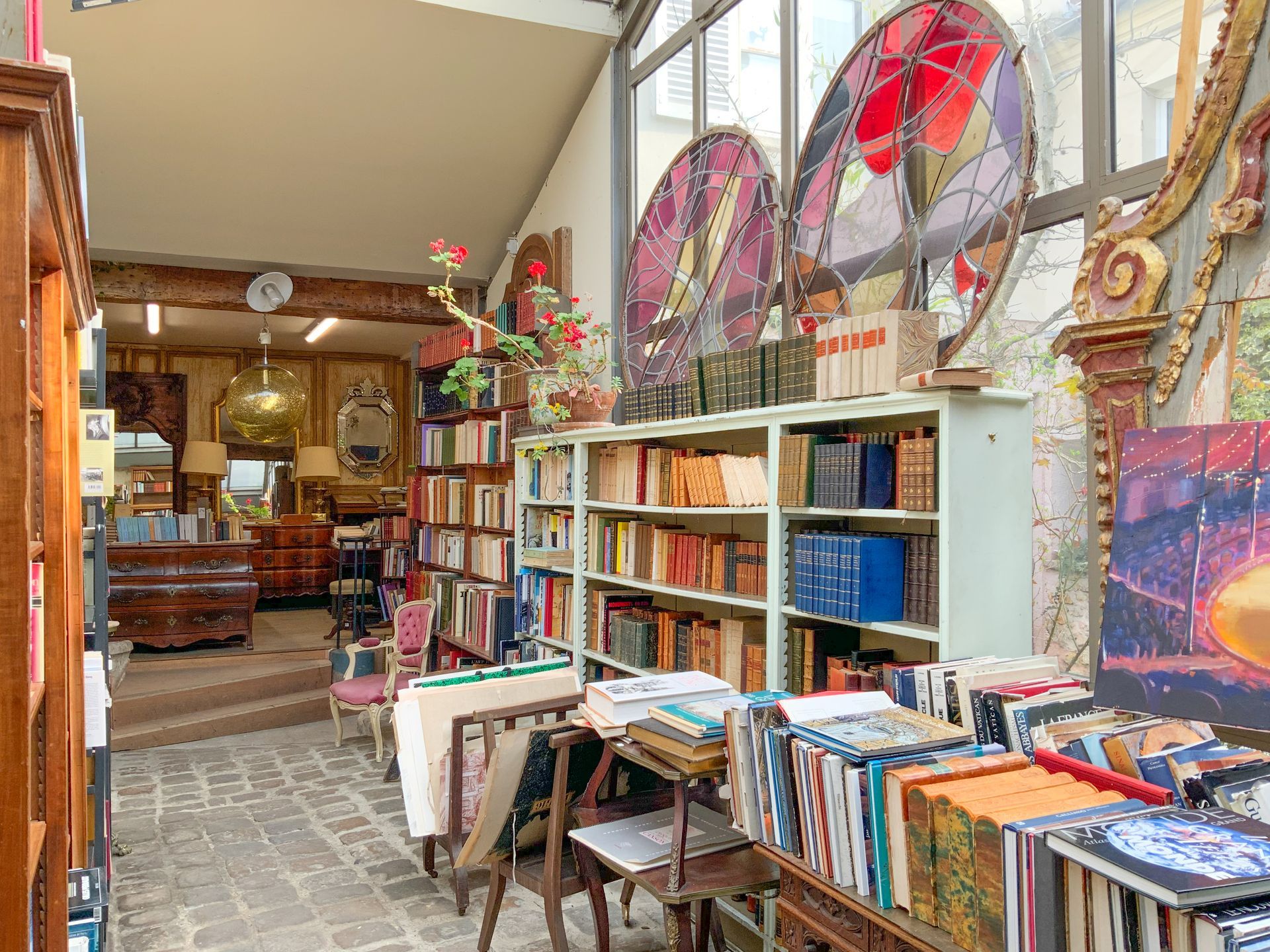 Deux grands vitraux ronds, divers livres exposés.