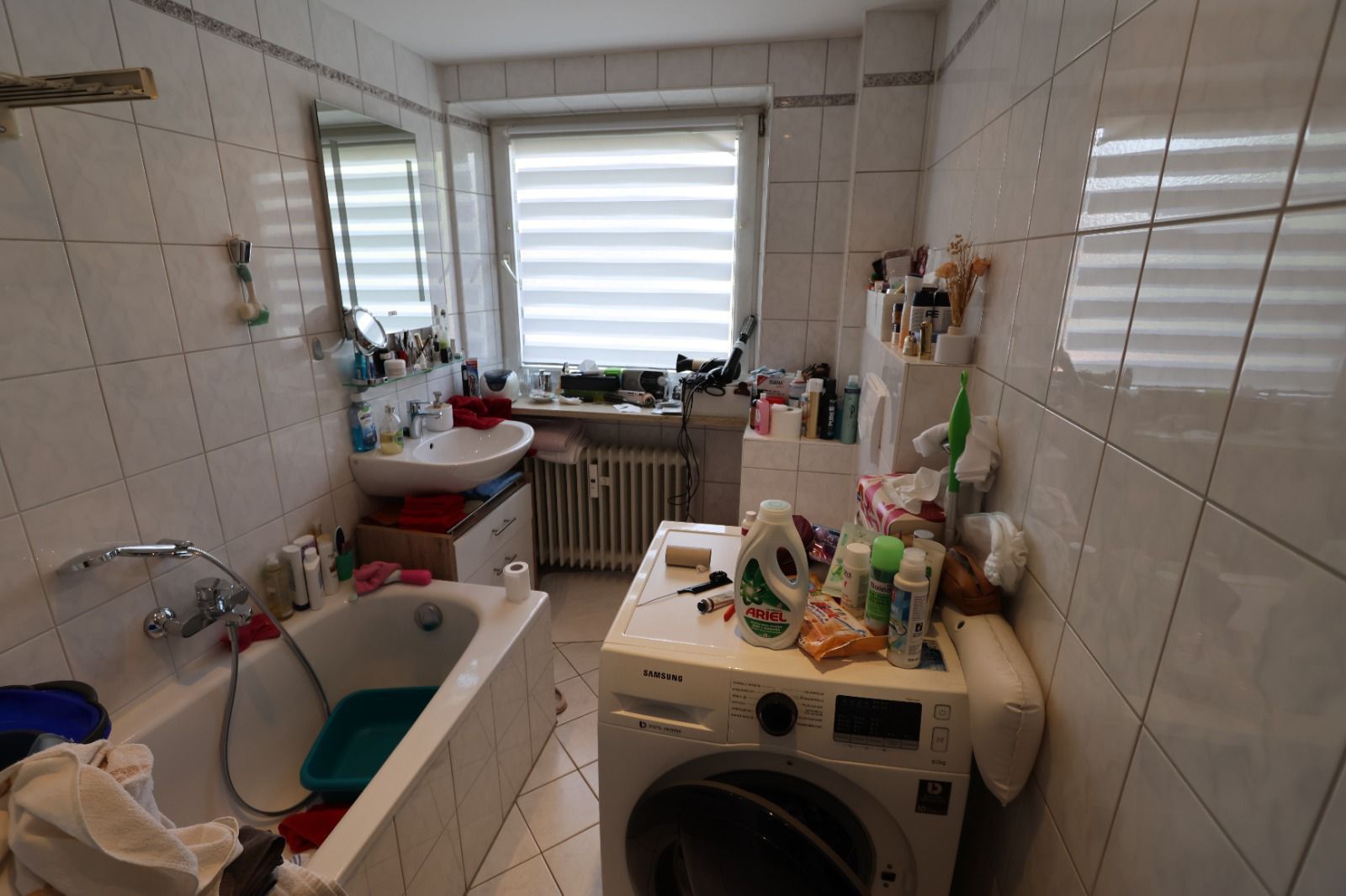 Ein gefliestes Badezimmer mit einer Badewanne und einer Waschmaschine.