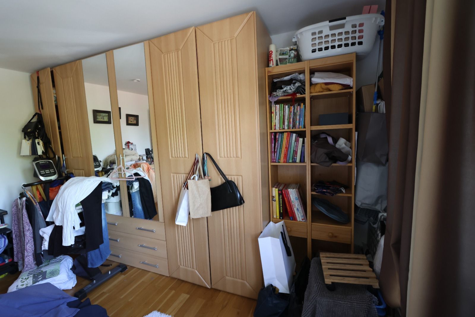 Ein großer Kleiderschrank mit Spiegeltüren und ein offenes Regal in einem Zimmer.
