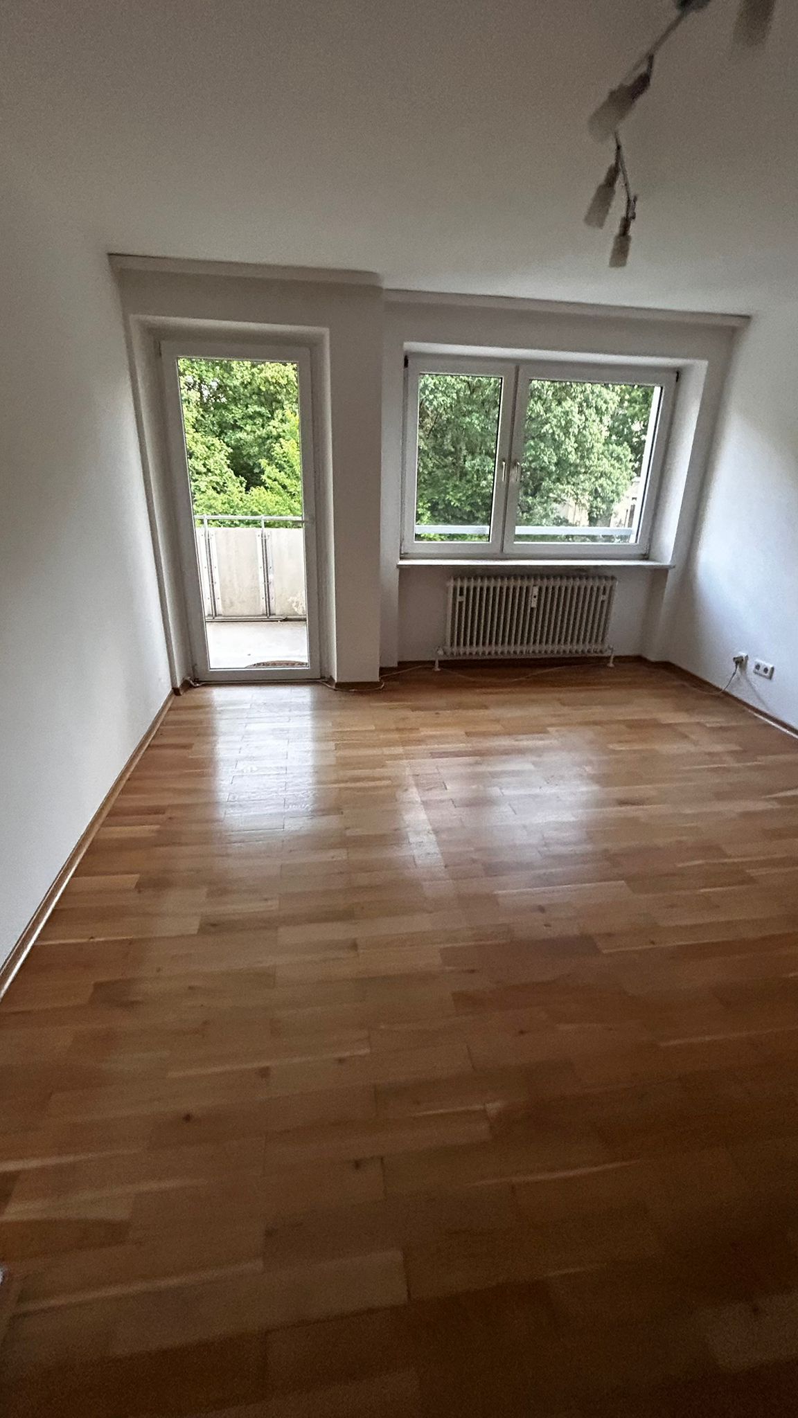 Ein Fenster mit Blick ins Grüne und einer hängenden Lampe im oberen Bereich.