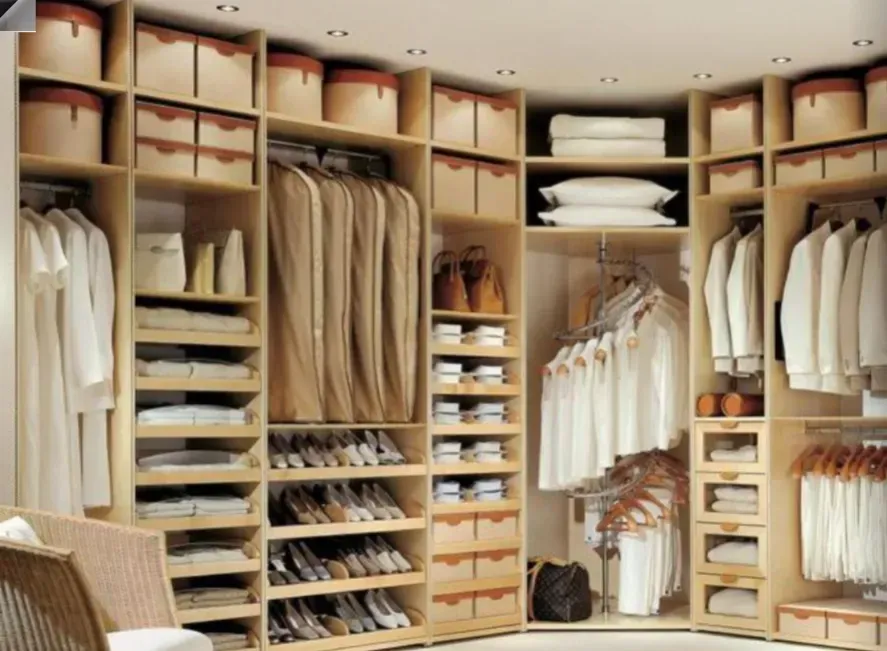 Armario empotrado con estantes, cajones y perchero para ropa beige y blanca en un vestidor ordenado.