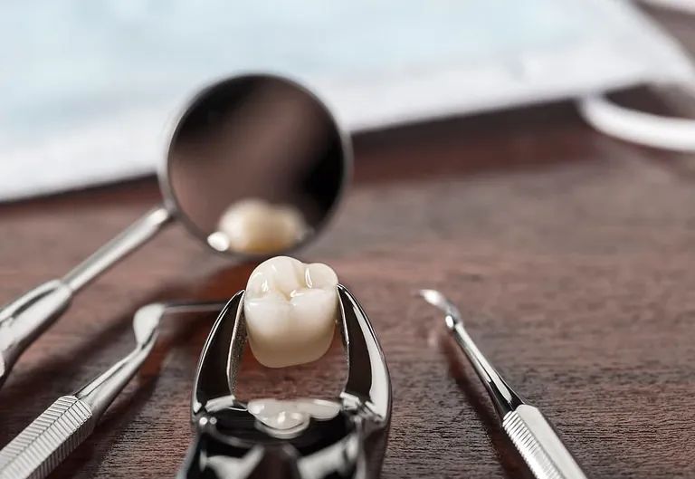 Un primer plano de un diente en un par de alicates dentales sobre una mesa de madera.