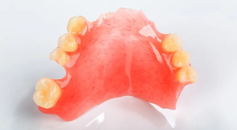 Un primer plano de una dentadura postiza con dientes sobre una superficie blanca.