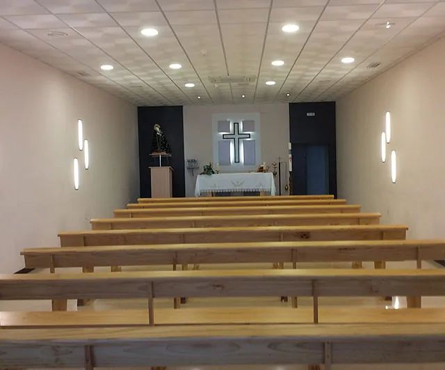 Una iglesia con bancos de madera y una cruz en la pared