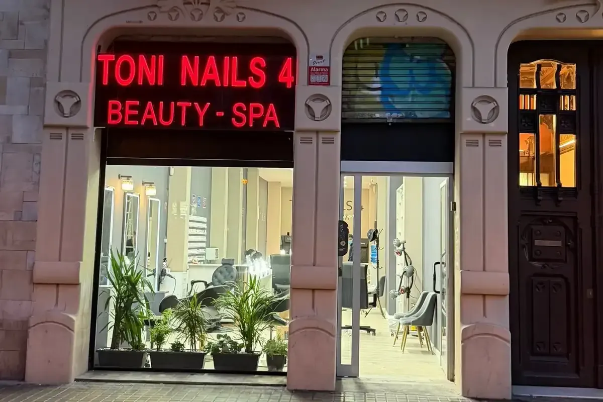 Escaparate de Toni Nails 4 Beauty-Spa con letrero de neón, escaparates de cristal, plantas en macetas y puerta cerrada.