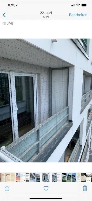 Balkon eines modernen Mehrfamilienhauses mit Glasgeländer und Sicherheitsnetz.