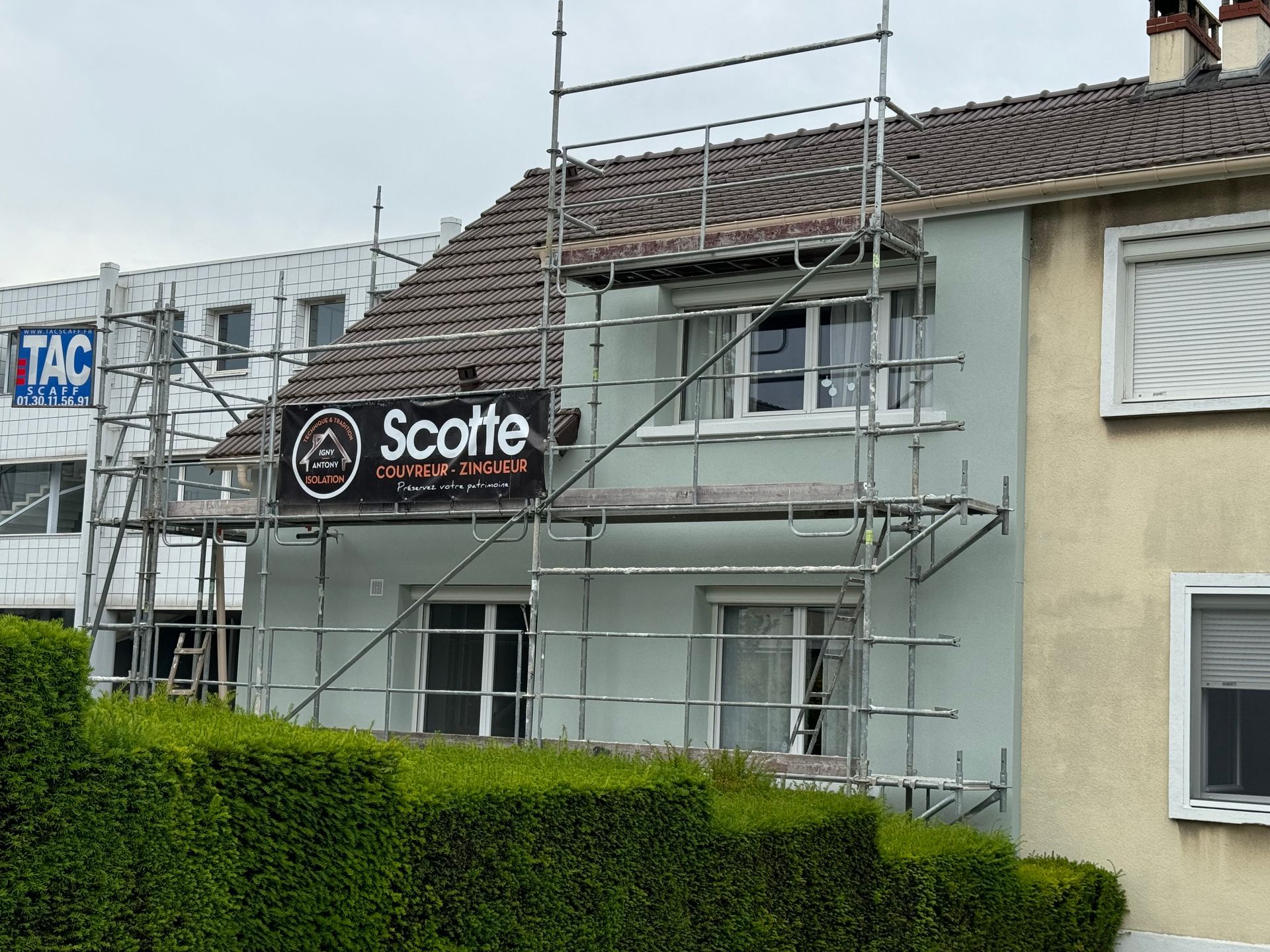 Maison à la façade peinte en vert avec échafaudages