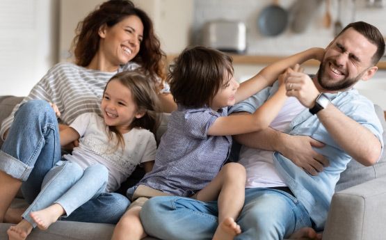 Una familia está sentada en un sofá jugando entre ellos.