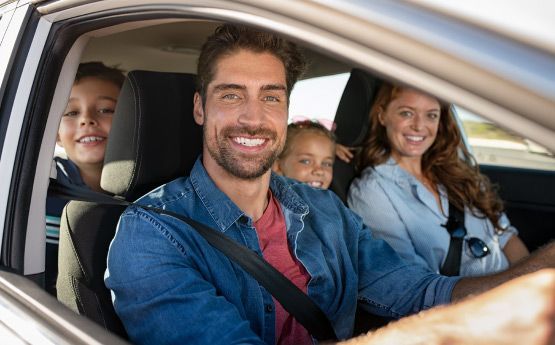 Una familia está sentada en el asiento trasero de un coche.