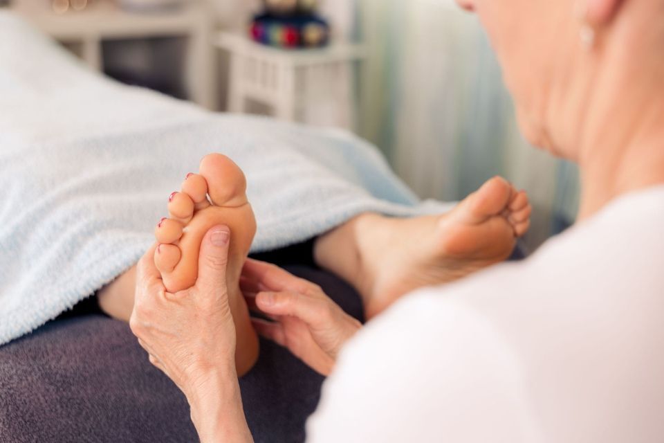 Hände massieren den Fuss einer Person auf einem Handtuch in einer Spa-Umgebung
