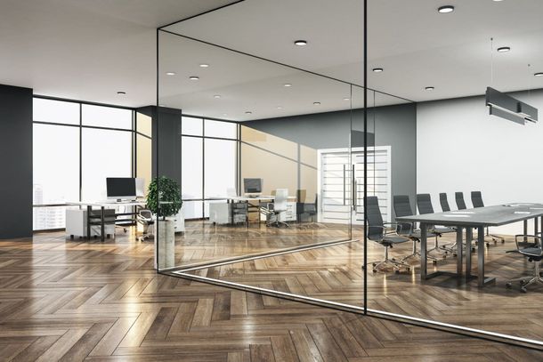 Una oficina moderna con una pared de cristal y suelo de madera.