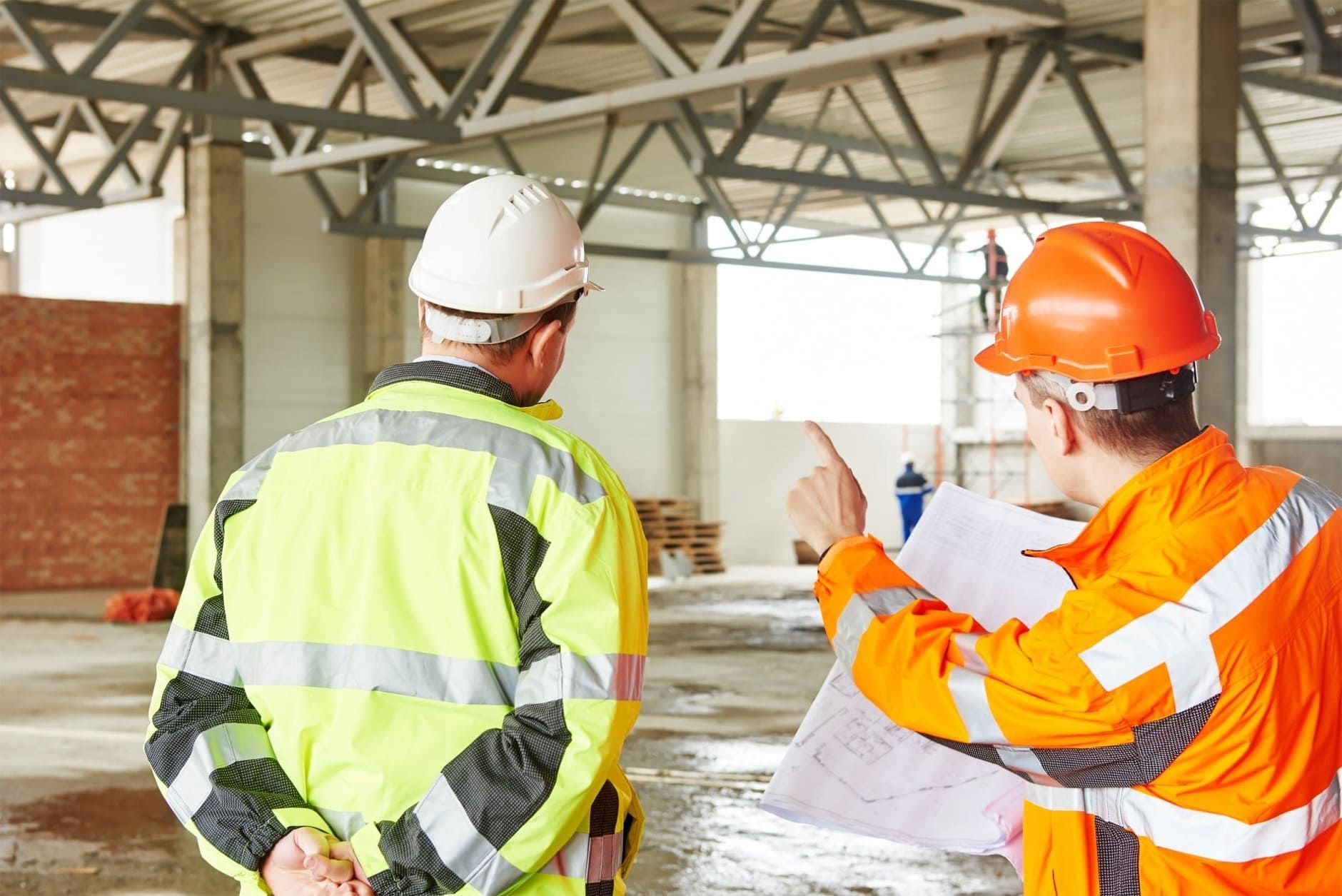 Dos trabajadores de la construcción están mirando un plano en un sitio de construcción.