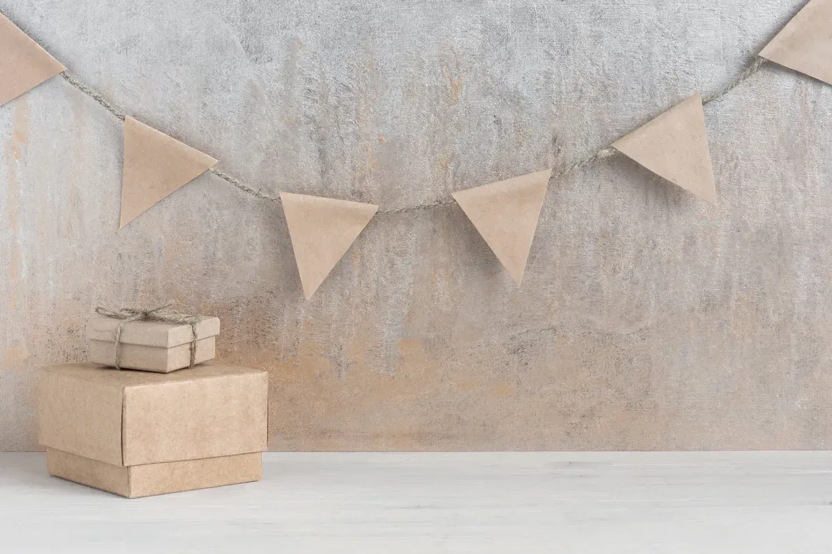 Cajas de regalo marrones con guirnalda de hilo sobre una pared de color tostado y blanco.