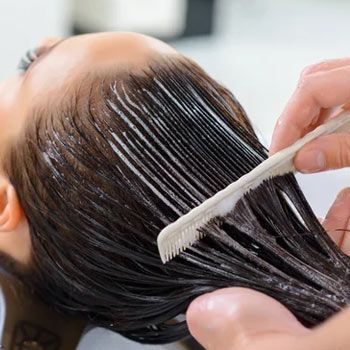 Una mujer se está tiñendo el pelo en una peluquería.
