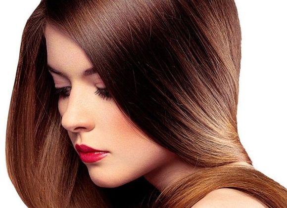 Una mujer con cabello largo y castaño y lápiz labial rojo mira hacia abajo.