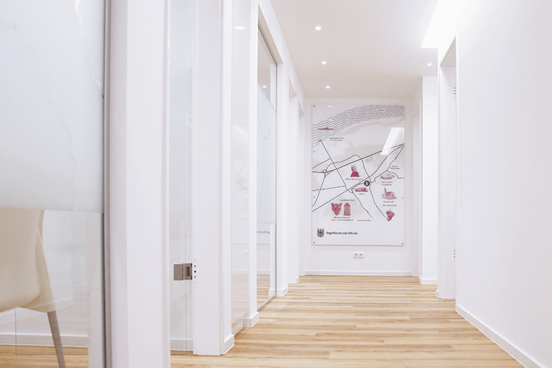 Heller Flur mit Holzboden, weißen Wänden und Türen sowie einer Landkarte an einer Wand.