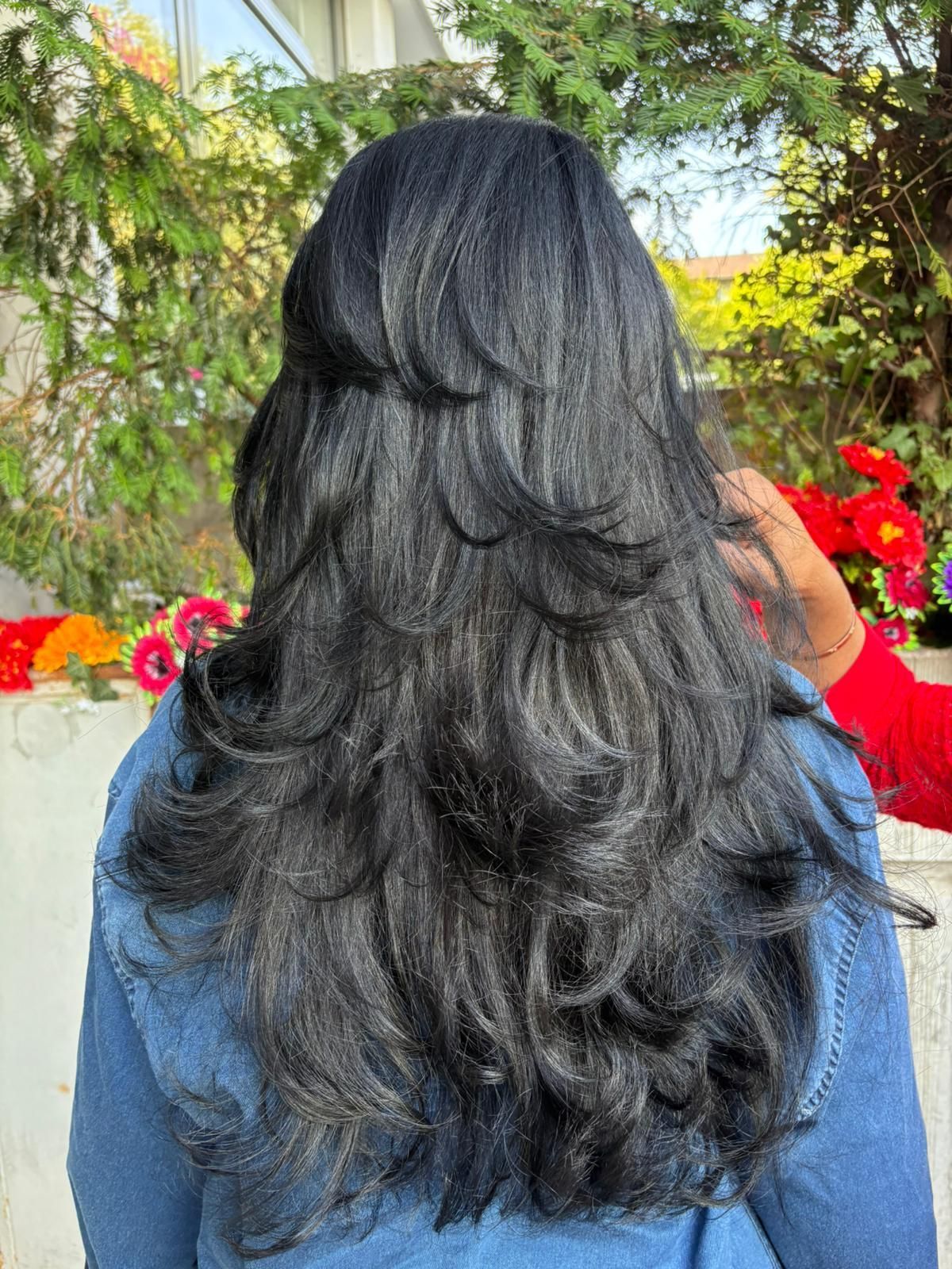 Coiffeuse coiffant les cheveux auburn d'une cliente (vue dans le miroir du salon)