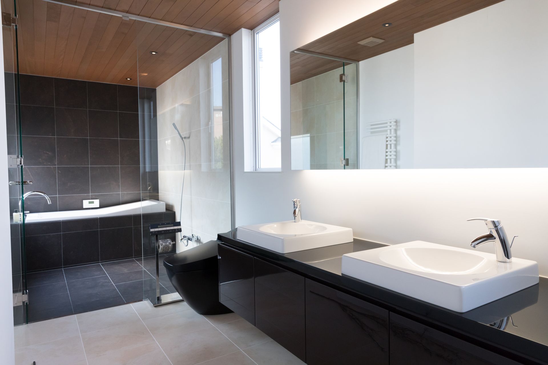 Salle de bains moderne avec une double vasque, un grand miroir,un meuble de lavabo noir, une baignoire et une douche.