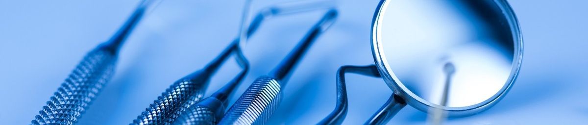 Un primer plano de un espejo dental e instrumentos dentales sobre un fondo azul.