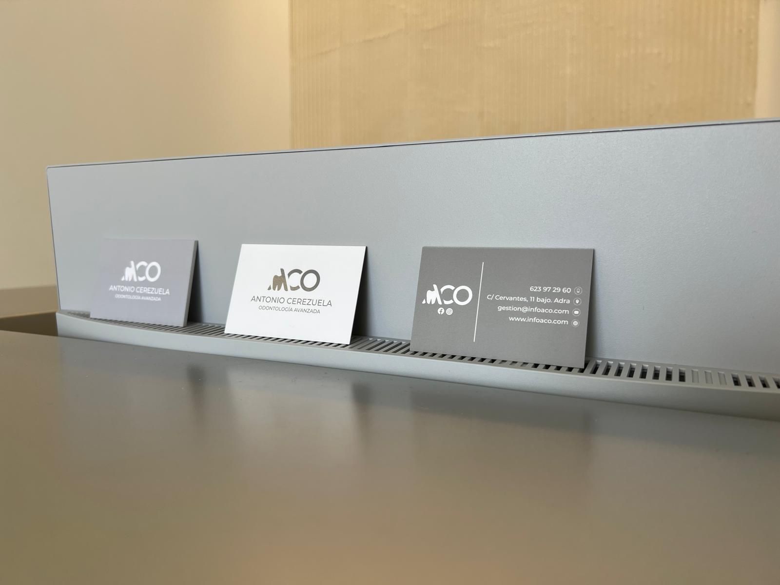 Hay tres tarjetas de visita en un estante sobre una mesa.