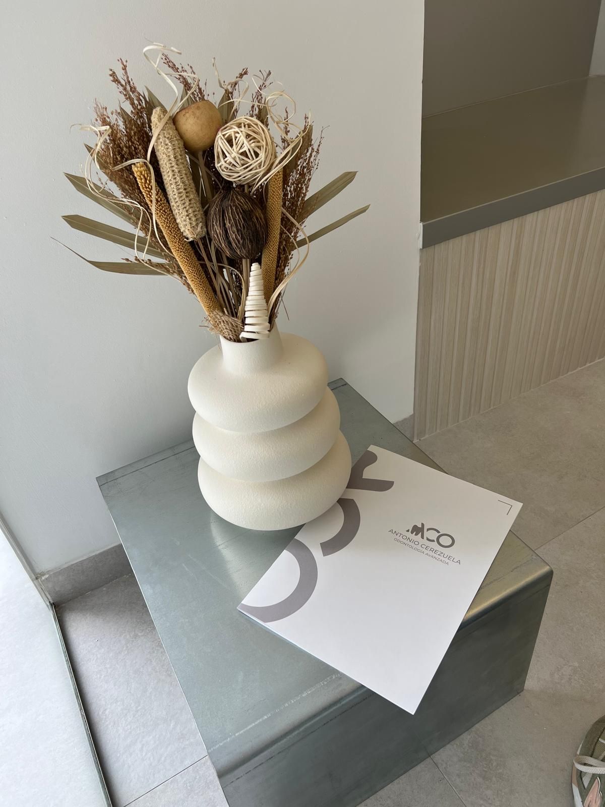 Un jarrón lleno de flores secas está sobre una mesa.