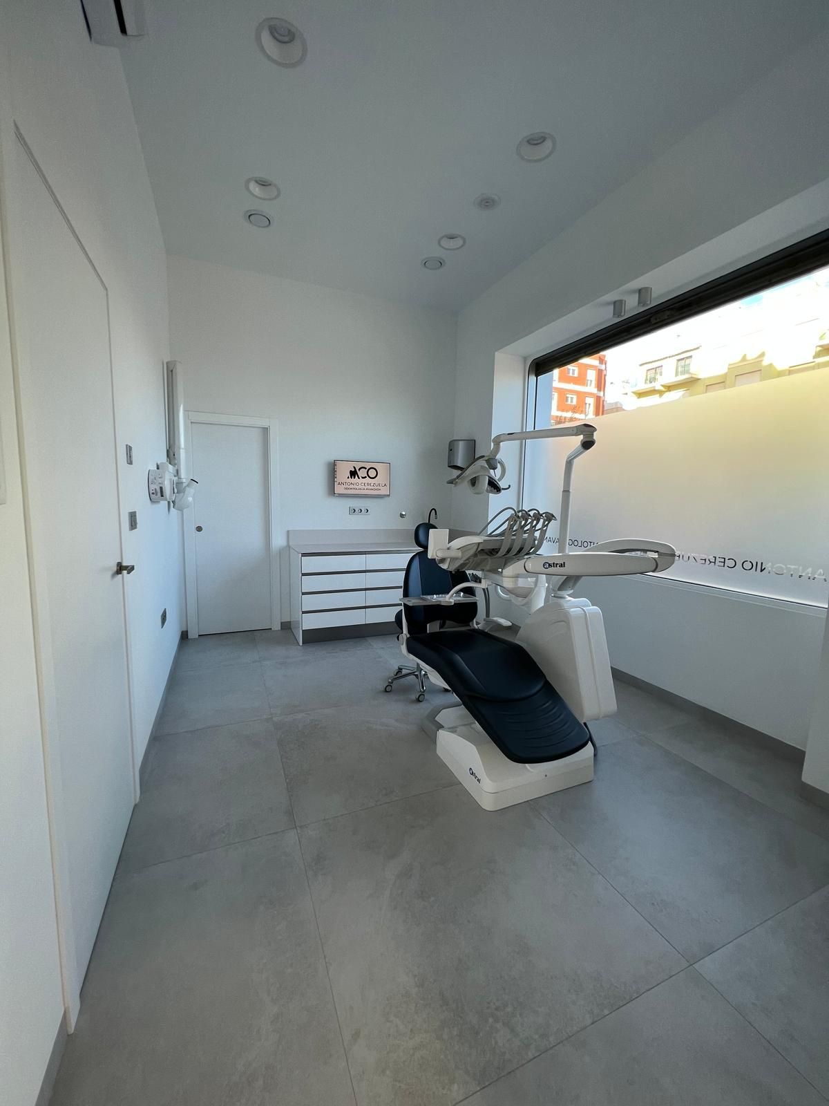 Un consultorio dental con un sillón dental y una ventana.
