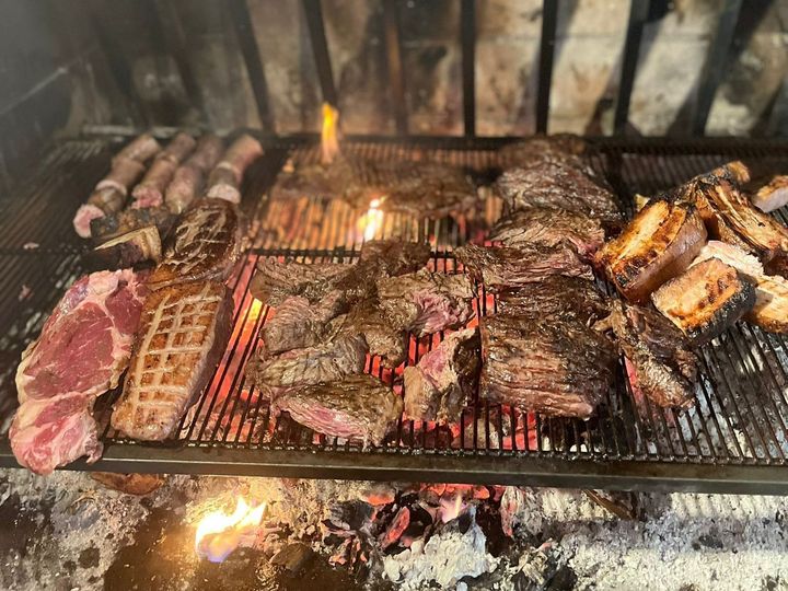 Des pièces de viande grillent au feu de cheminée