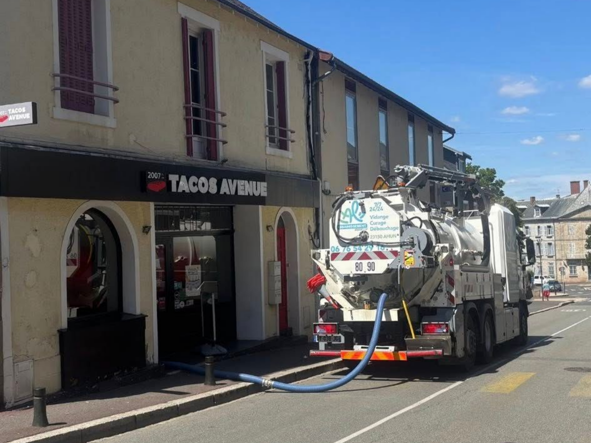 Un camion d'assainissement est stationné devant un restaurant de tacos.