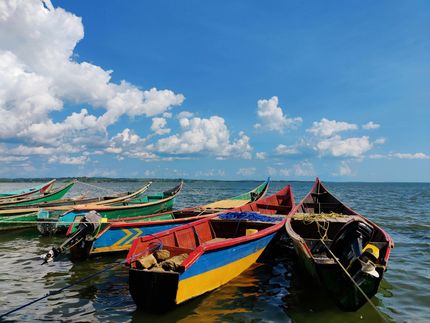 Colorful wooden fishing boats on calm water under a bright blue sky with clouds