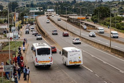 Busy highway with cars and buses on a curved road, seen from an overpass in a hilly area