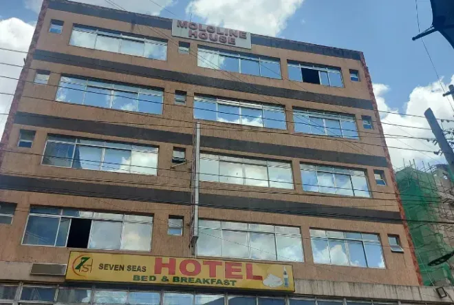 Multi-story brick hotel building with large windows and a yellow sign at street level