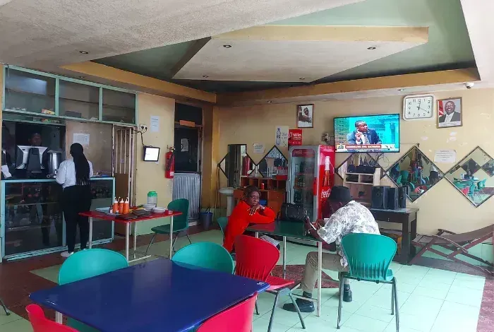 Casual restaurant interior with people seated at tables, TVs on the wall, and red Coca-Cola decor.