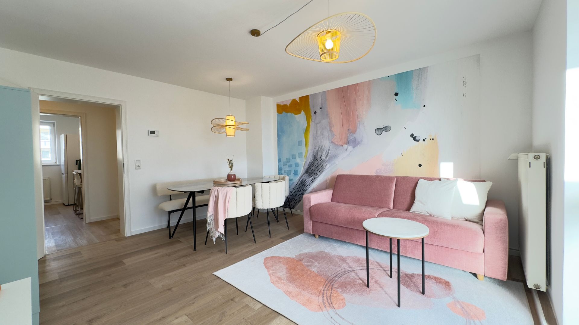 Wohnzimmer der Ferienwohnung Goldberg mit rosa Sofa, Wandgestaltung und gemütlicher Einrichtung