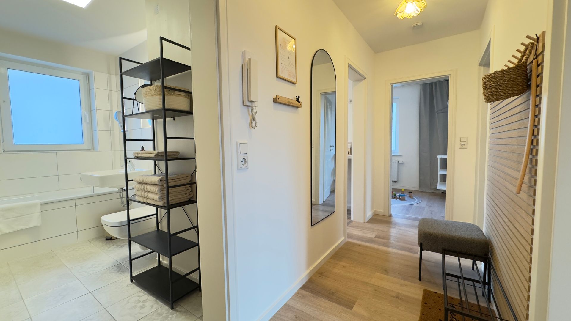 Gesamtansicht vom Flur ins das moderne Badezimmers mit Badewanne