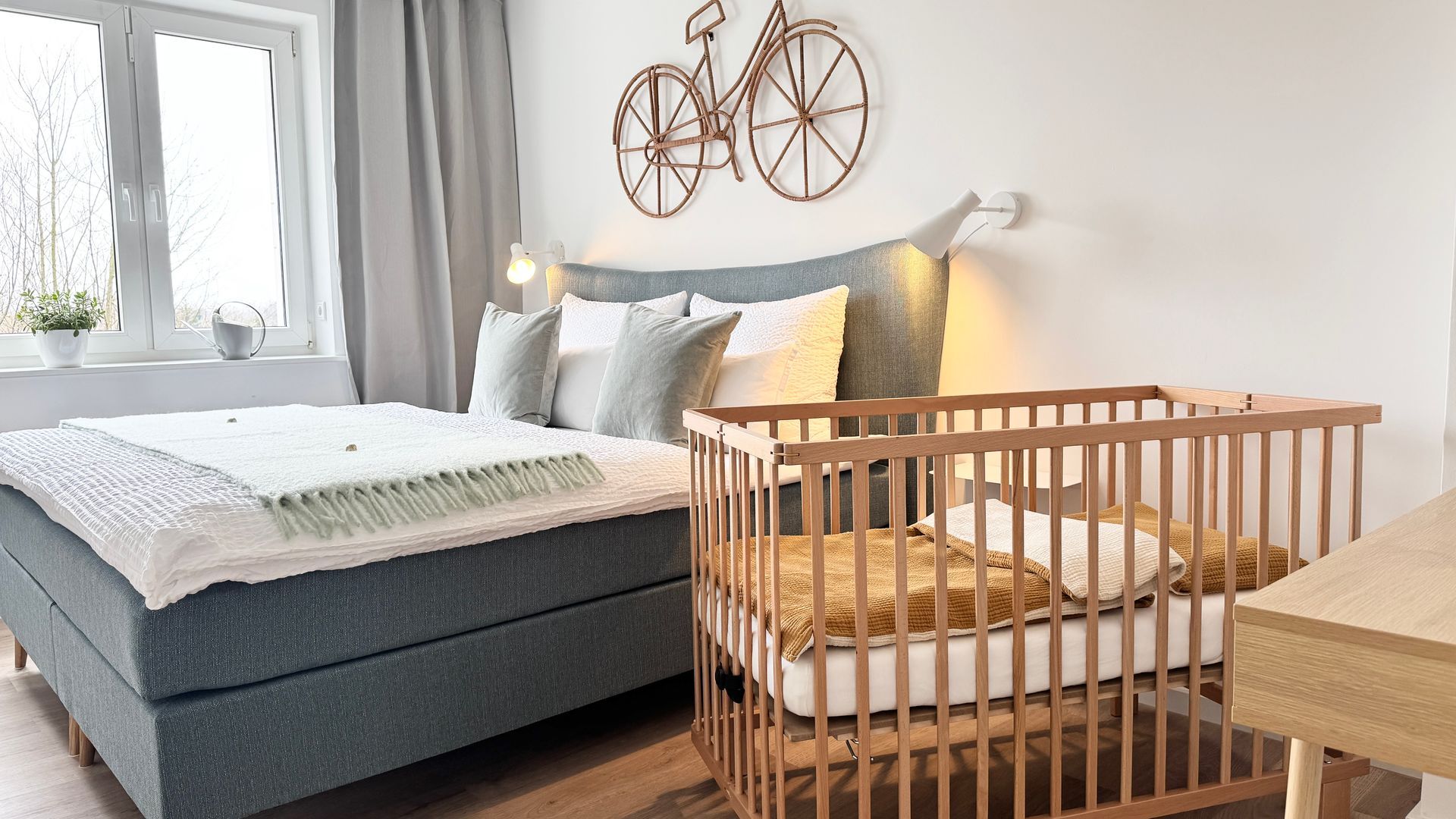 Babybett neben Boxspringbett im Elternschlafzimmer