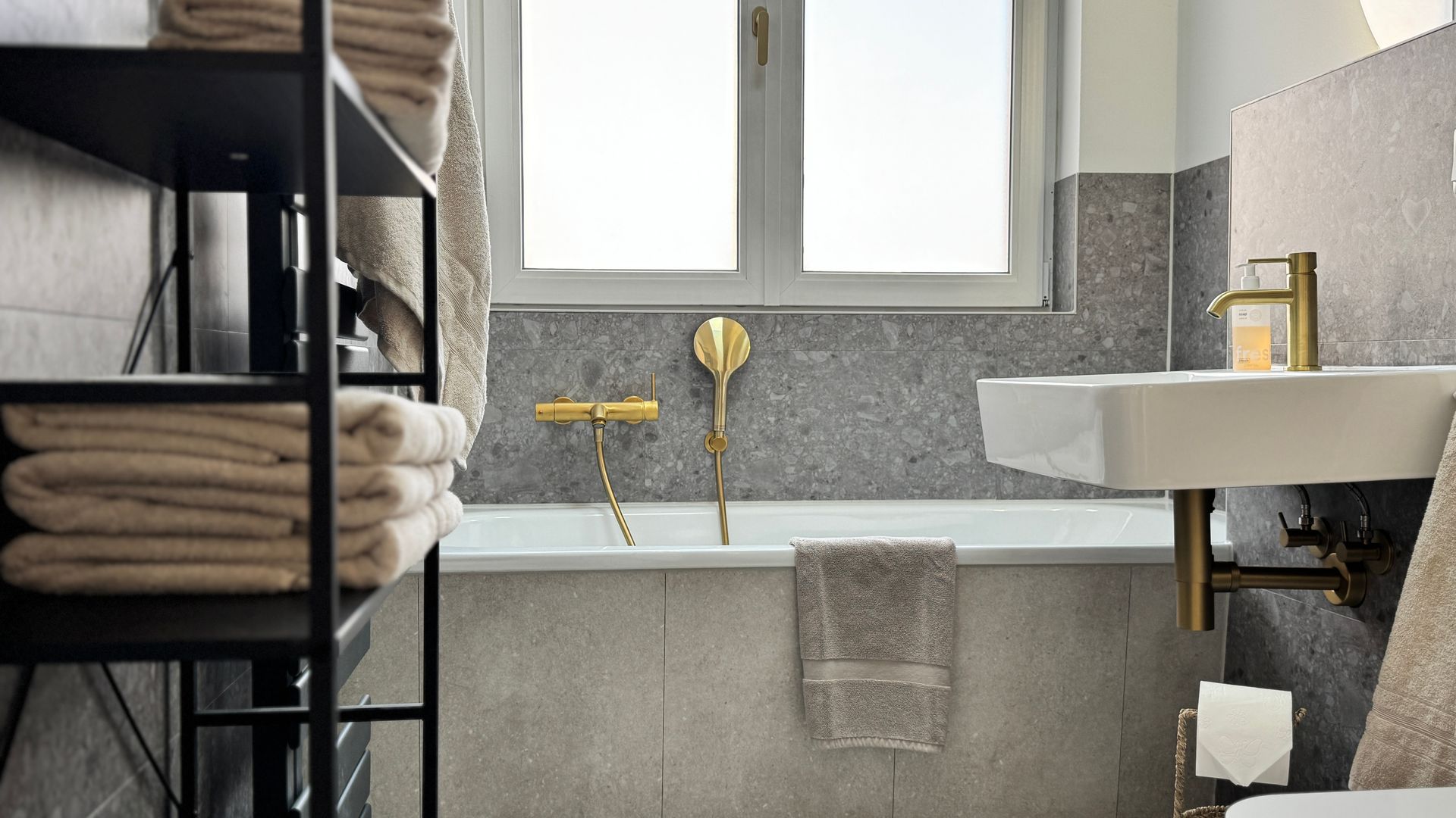 Badezimmer mit Badewanne und Waschbecken, im Hintergrund Milchglasfenster