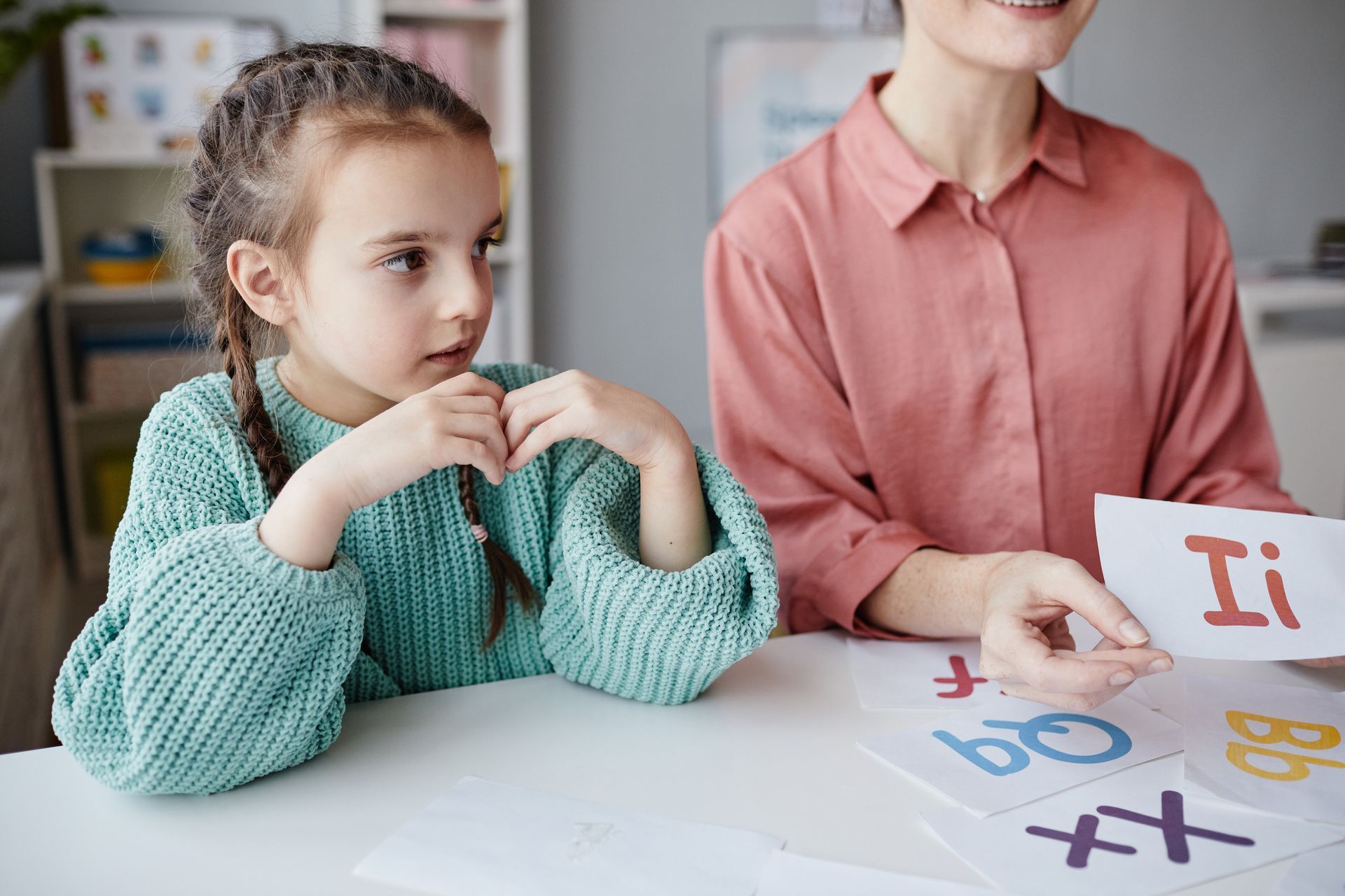 Una niña está sentada en una mesa con una mujer.