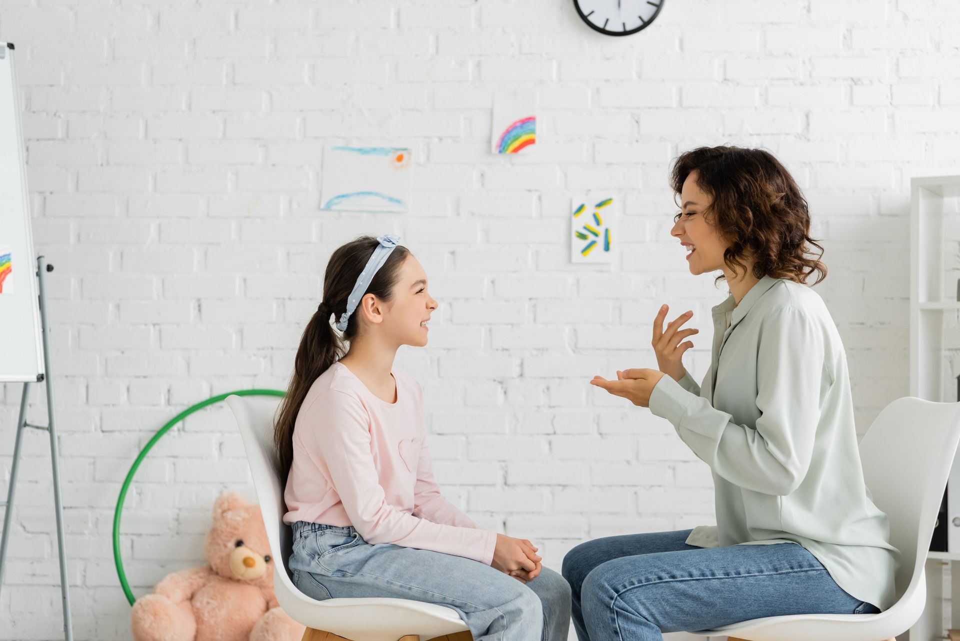 Una mujer está hablando con una niña que está sentada en una silla.
