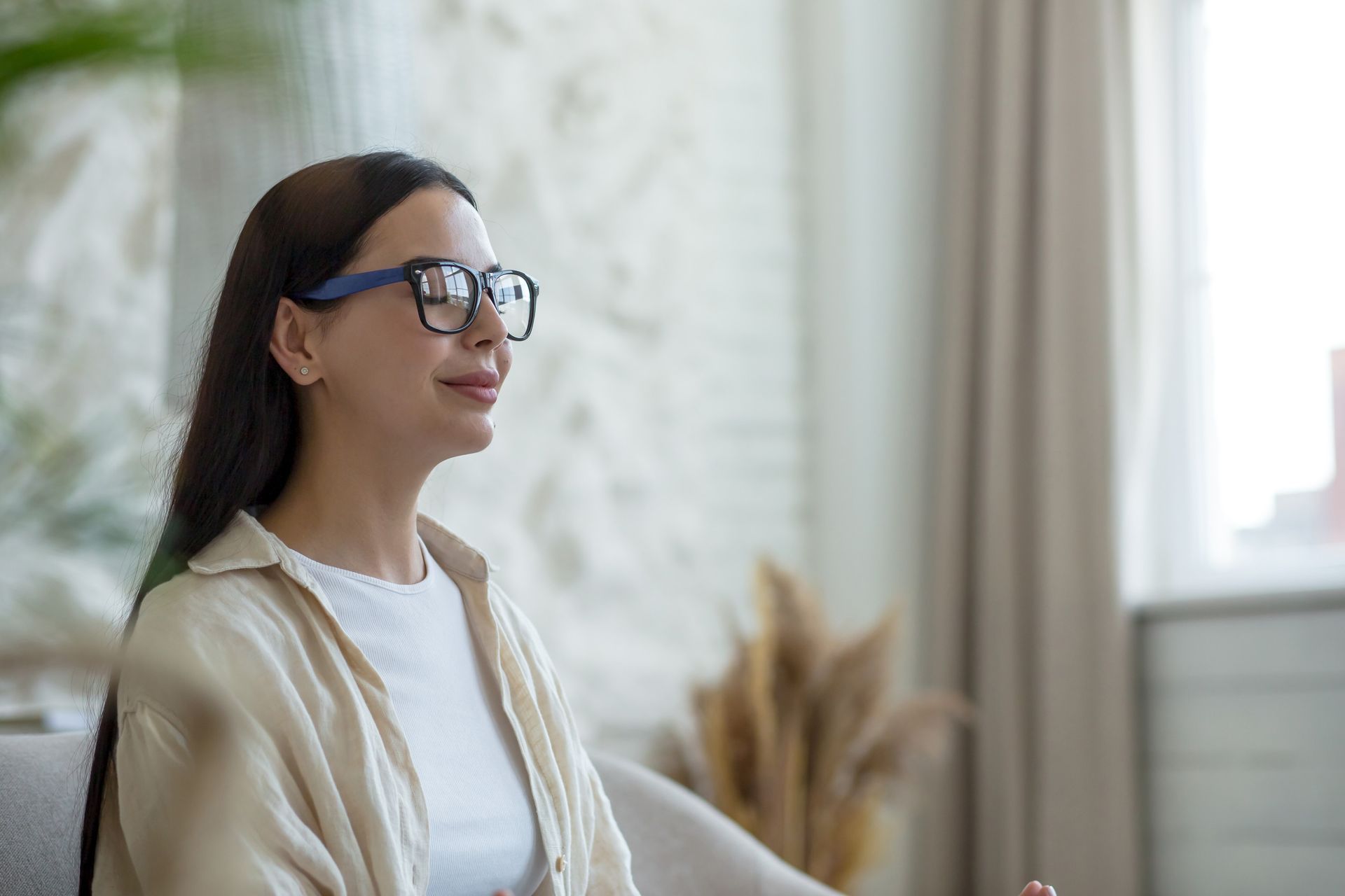 Una mujer con gafas está sentada en un sofá en una sala de estar.